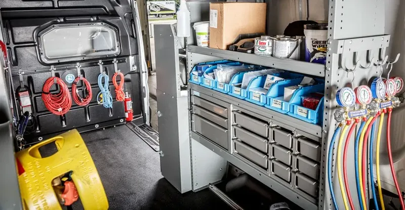 Van interior shelving wall with parts bins, drawer banks and hose reels