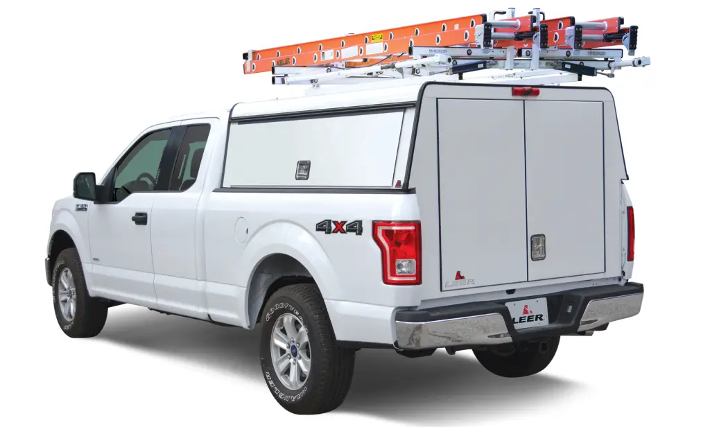 White Ford F-150 with a LEER enclosed commercial cap and ladders on roof-mounted racks