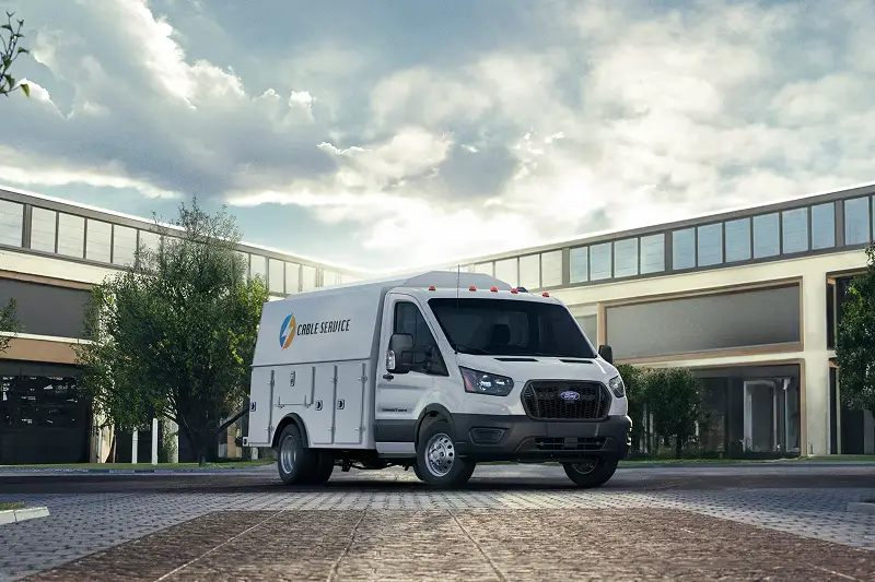 White Ford Transit with an enclosed walk-in service body parked outside a business park